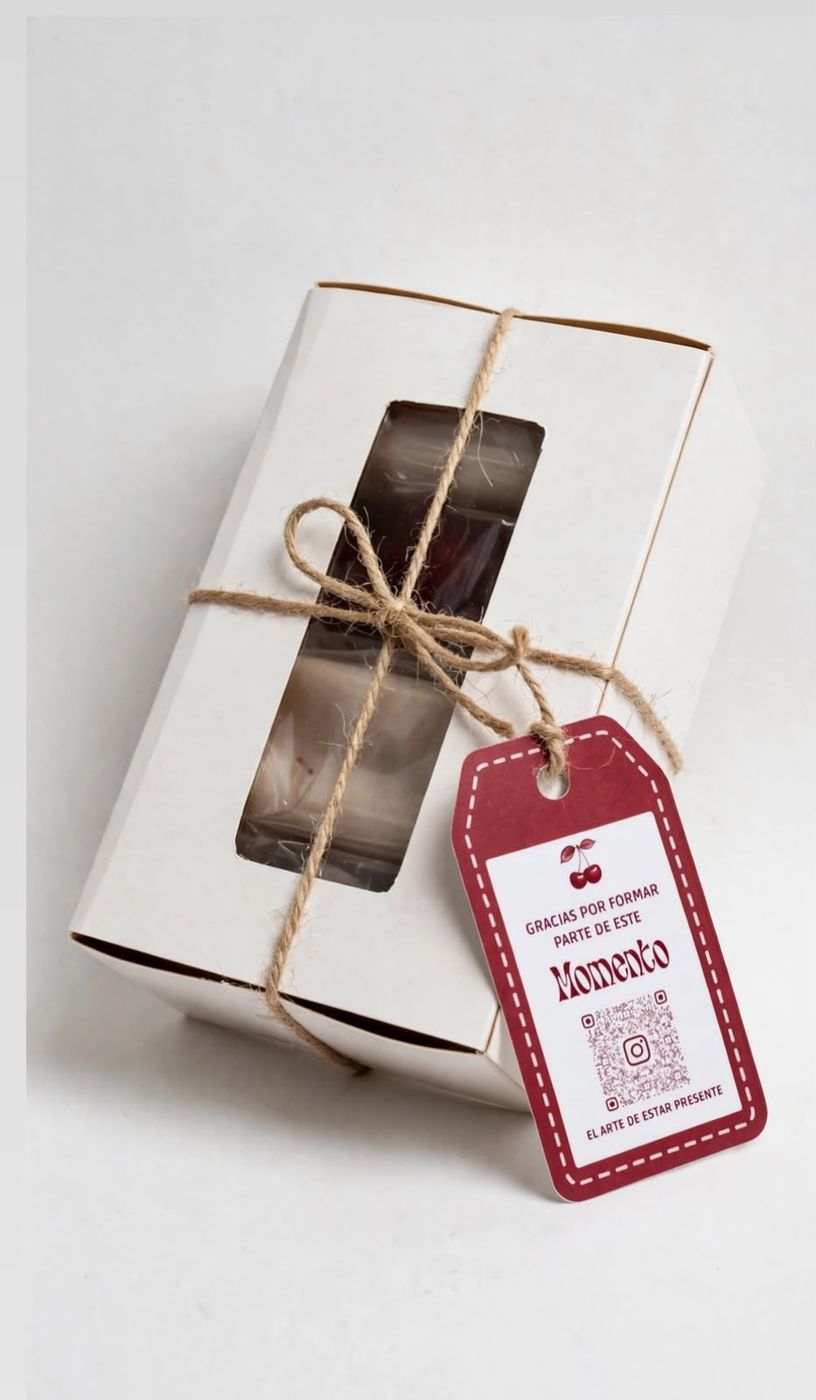 Caja blanca de Momento con visor, amarrada con cordel y la etiqueta burdeo «Gracias por formar parte de este Momento».
