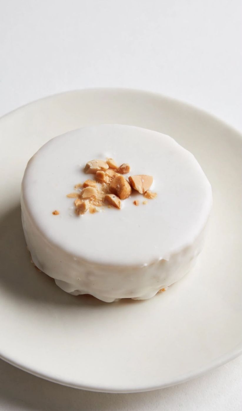 Alfajor Bon o Bon de Momento con baño de chocolate blanco y maní picado, sobre un plato blanco.